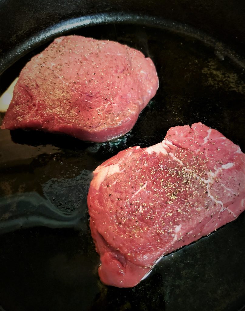 Home Chef Roasted Garlic Butter Steak - searing steaks in cast iron
